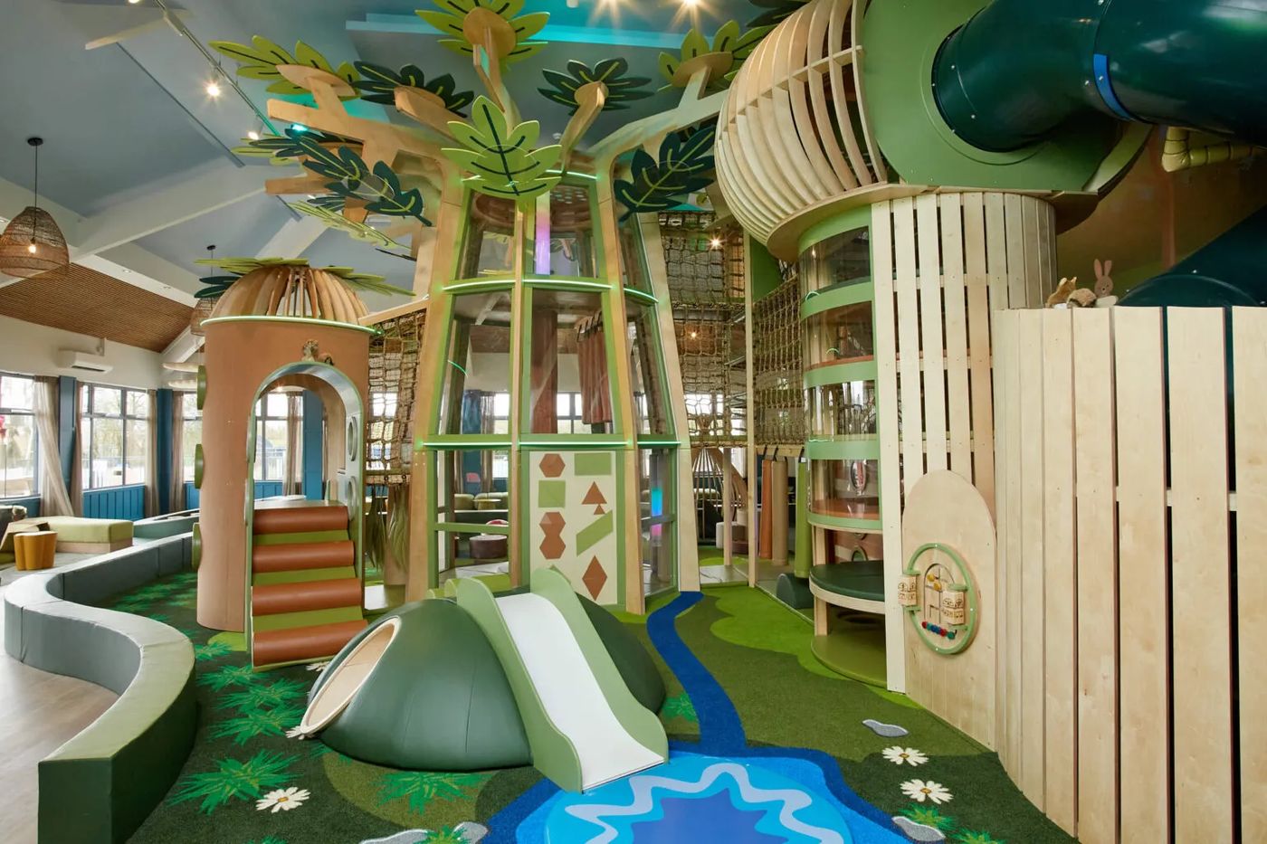 Nature-themed indoor playground system with tree play structure and slides