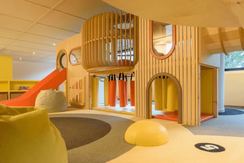 Wooden play structure with slide, climbing holds and net play elements